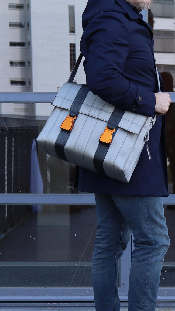 silver seatbelt messenger bag from the brand eKodoKi, carried by male model, as mobile banner
