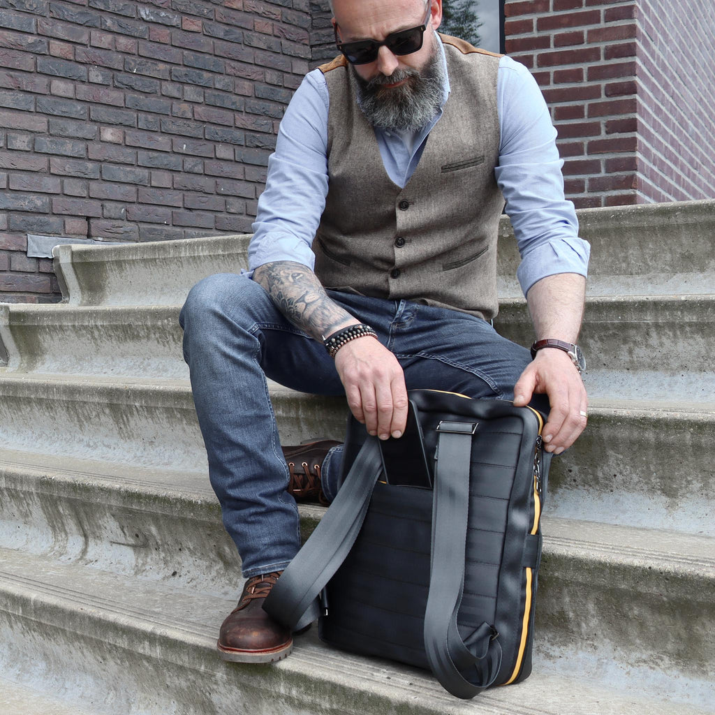 black seatbelt backpack L on male fashion model shoulders sitting and putting his phone in the back pocket eKodoKi RE-BELT