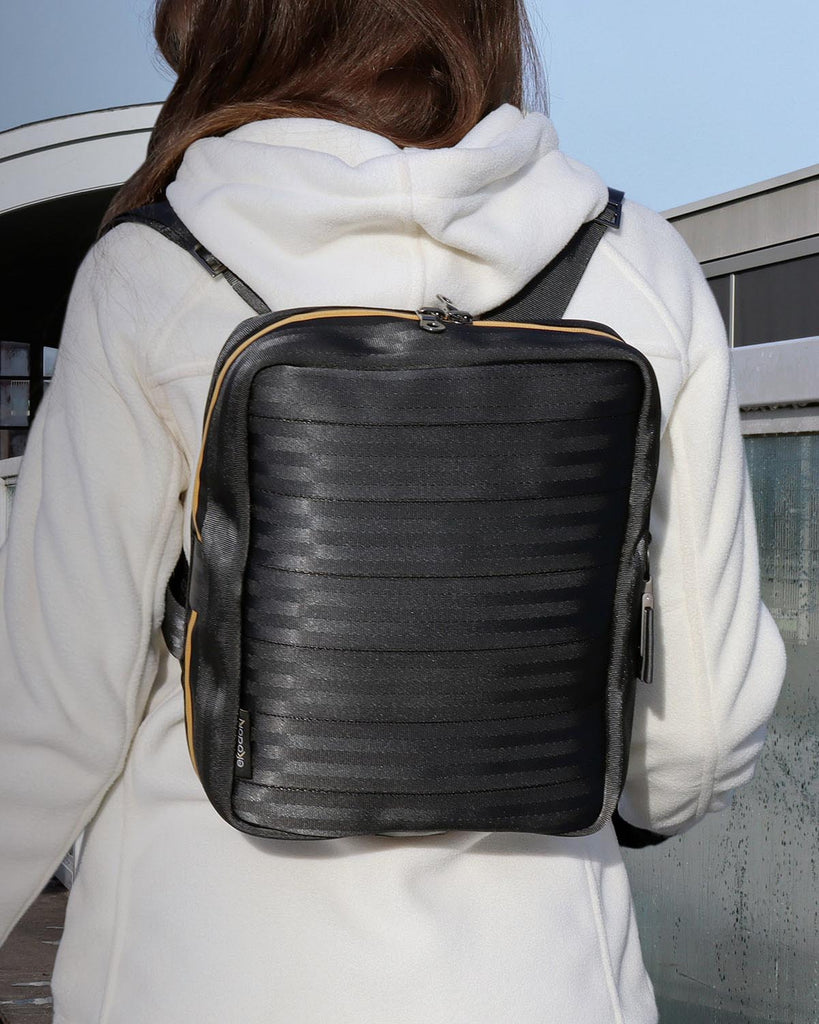 black seatbelt backpack and messenger bag from the brand eKodoKi, worn each by a fashion model, as shaded mobile banner