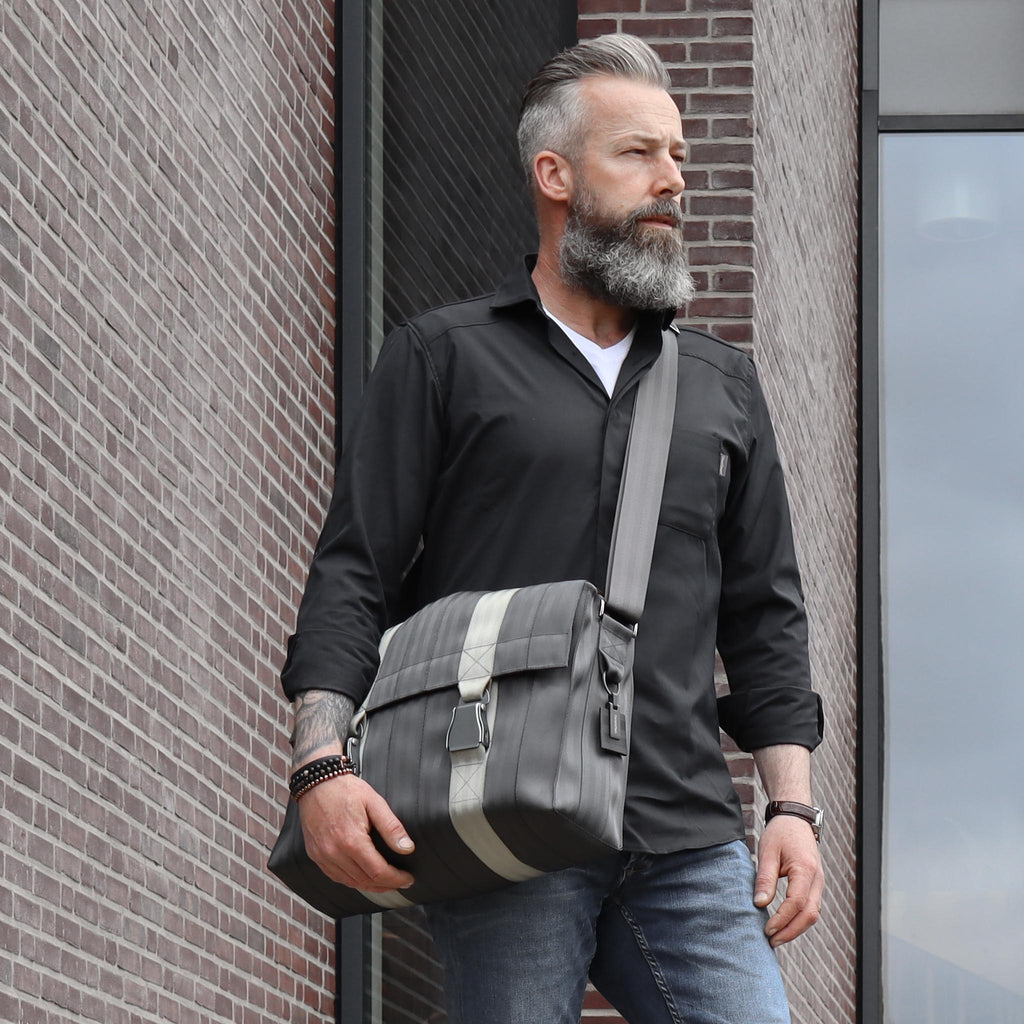 black seatbelt messenger bag L on male fashion model standing, with his arm down on the bag  eKodoKi RE-BELT