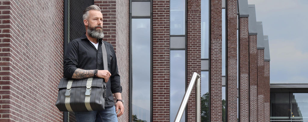 black seatbelt messenger bag L on male model's shoulder standing, desktop banner, eKodoKi RE-BELT