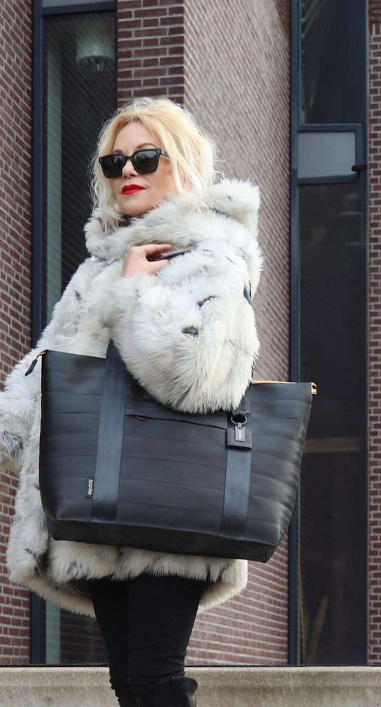 Black seatbelt tote bag from the brand eKodoKi, carried by female model on her shoulder, as mobile banner