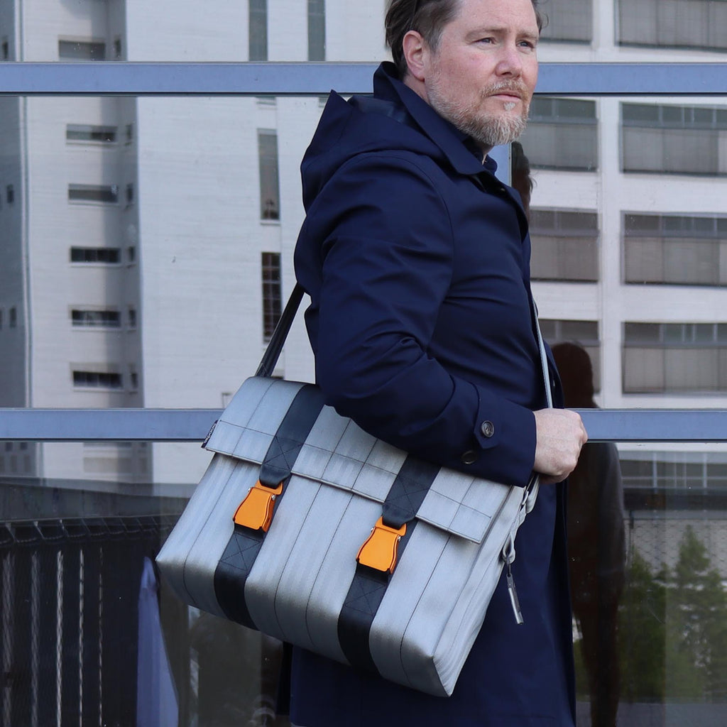 sand seatbelt messenger bag L on male fashion model standing, with his arm laying on the bag eKodoKi RE-BELT
