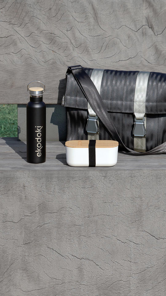 seatbelt bag, reusable bottle and lunchbox from the brand eKodoKi, on a bench, as mobile banner to illustrative example of the bundles offered by the D2C shop
