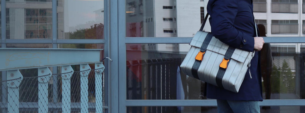 silver seatbelt messenger bag from the brand eKodoKi, carried by male model, as desktop banner