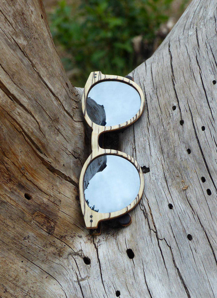 wooden sunglasses from the brand eKodoKi laying on a piece of wood in nature, used as mobile banner