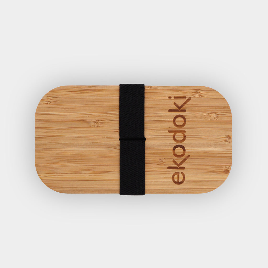 white lunchbox 700ml 24oz with natural bamboo lid and built-in black elastic fabric strap wrapped around flatlay eKodoKi BENTO