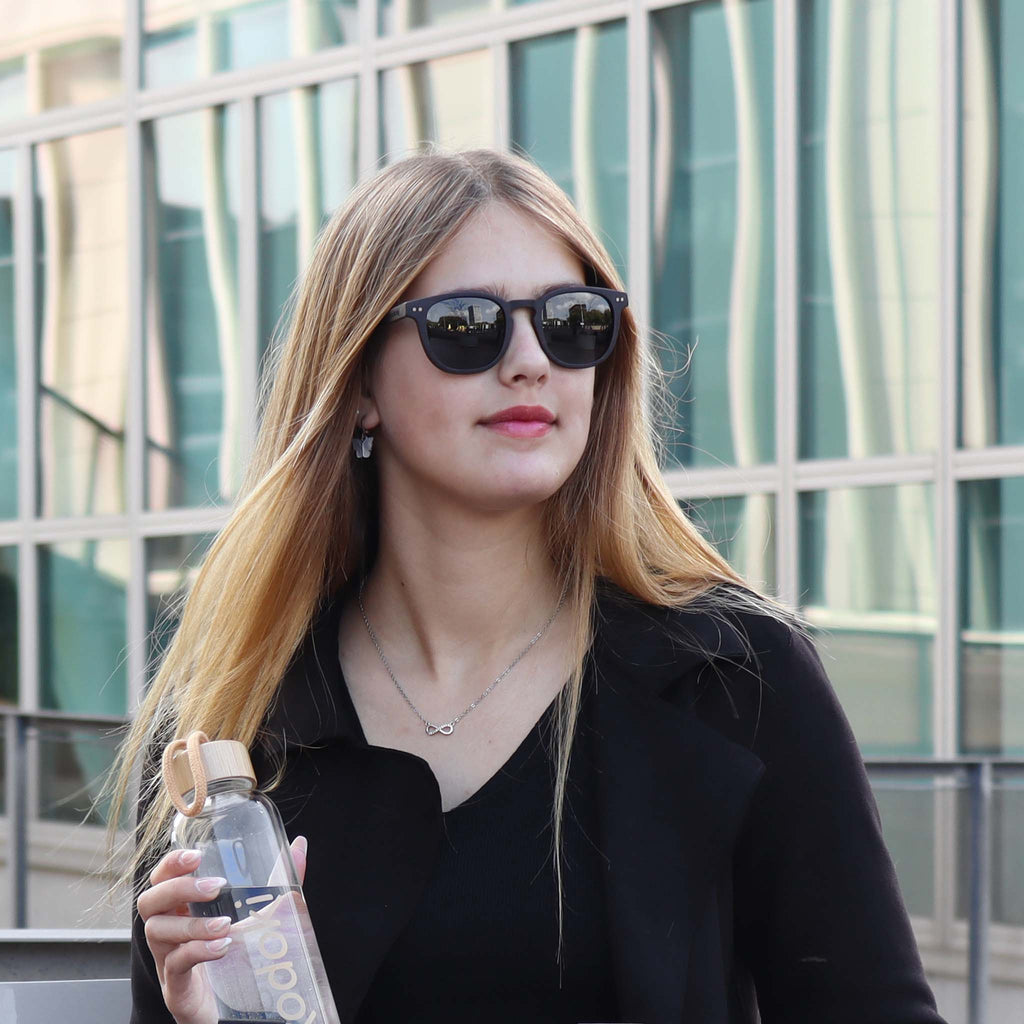 wooden sunglasses pantos style ebony wood smoke lenses on female fashion model holding a bottle eKodoKi COSMO